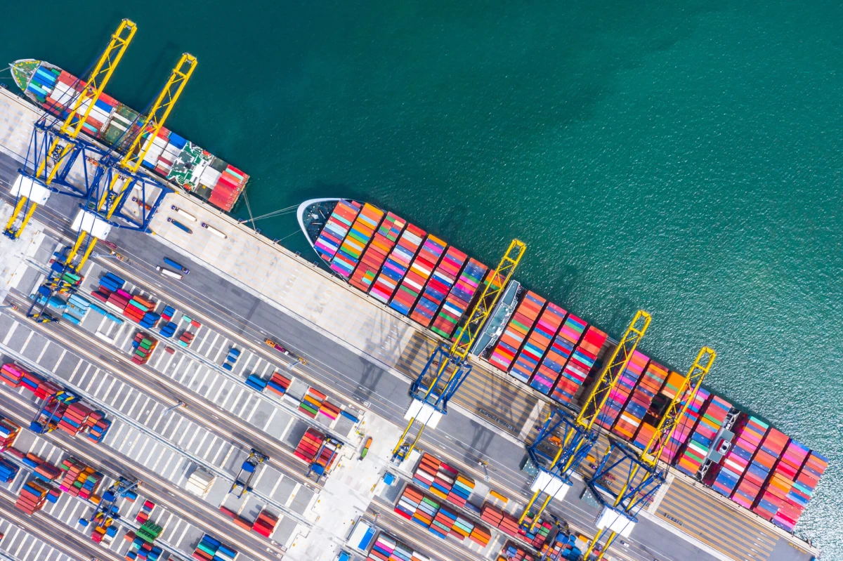 Container cargo ship loading and unloading Aerial top view of boat business commerce logistic commercial import and export freight transportation by container cargo ship in open